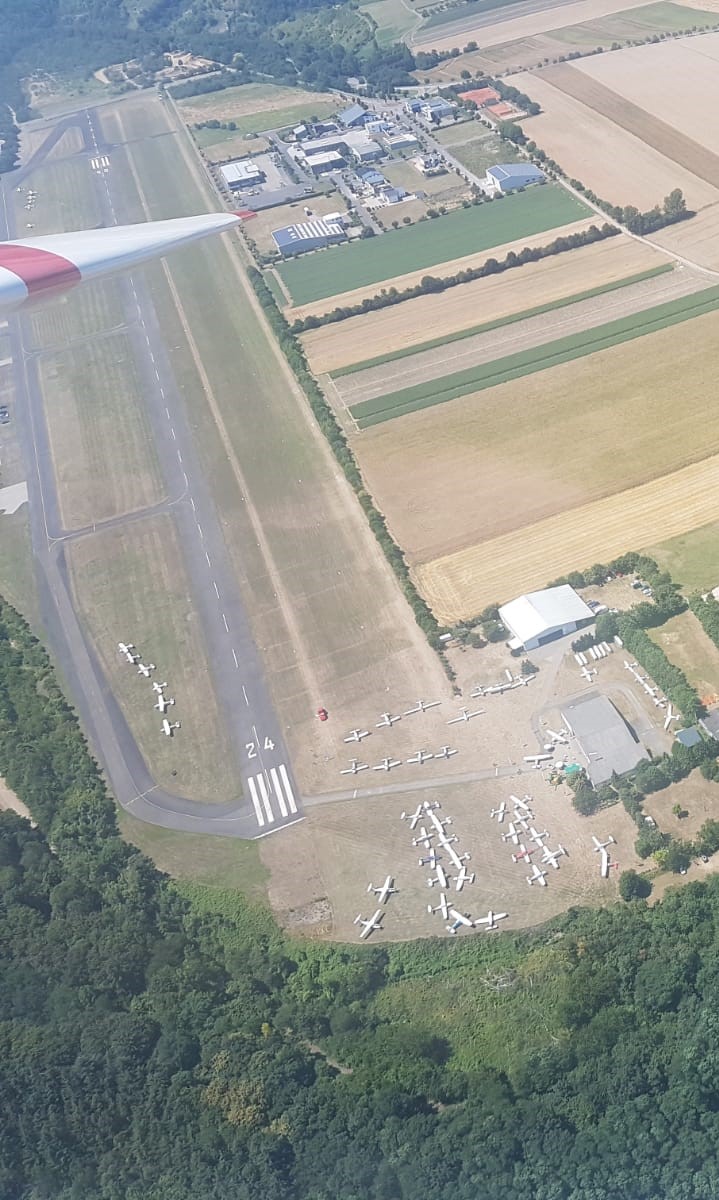 Ganz schön was los beim Wingly-Fly-In 2018 Blick aus einem Segelflugzeug auf den Flugplatz Koblenz-Winningen. Um die Hallen des Aero-Club Koblenz am unteren Bildrand stehen viele Motorflugzeuge.